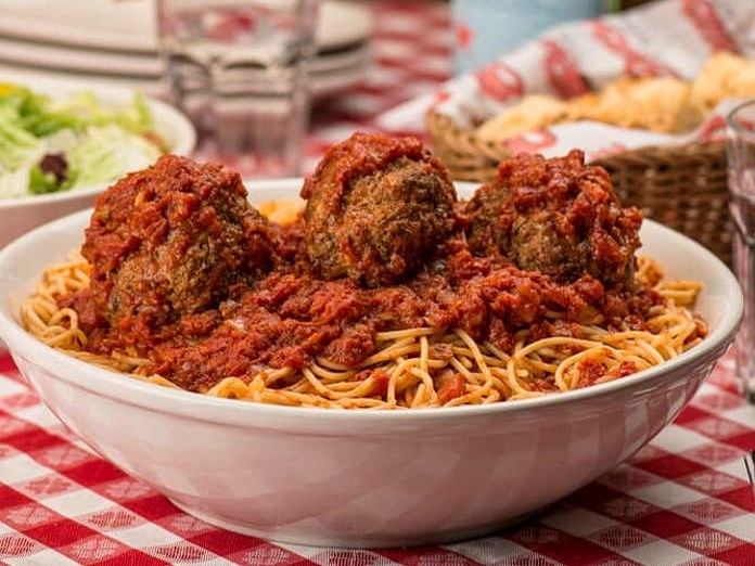 A large bowl of spaghetti with three giant meatballs