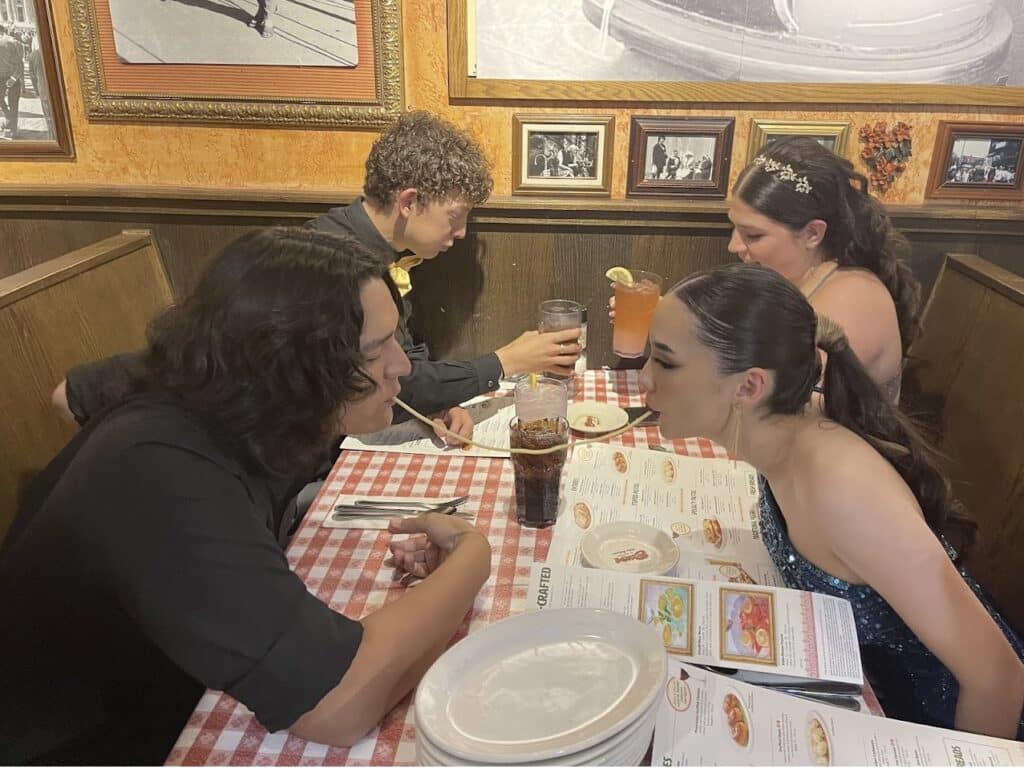 A couple sharing a noodle from across the table at Buca di Beppo