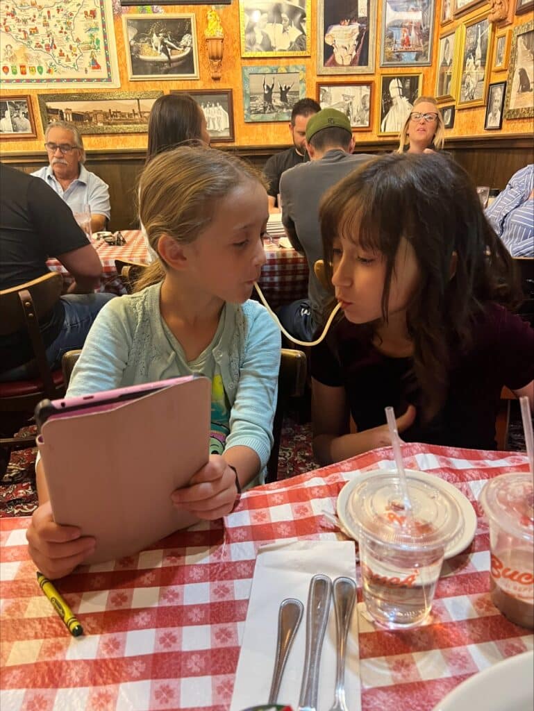 Two girls trying Buca's pasta challenge with an ipad in their hands