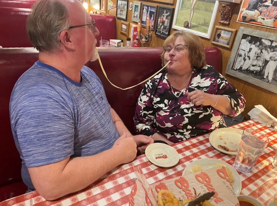 A couple sharing a noodle and sitting next ot each other at Buca