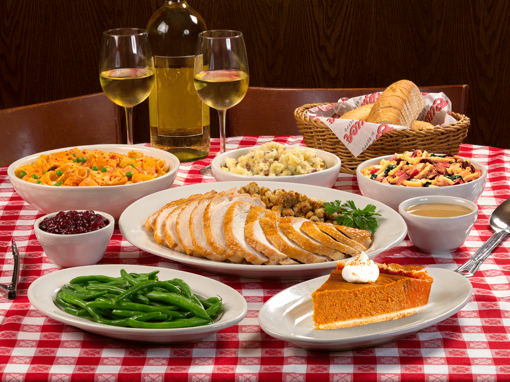 A table full of Thanksgiving food with two glasses of wine